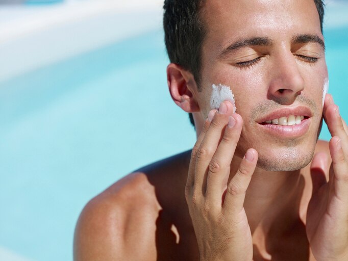 Young man applying lotion to face