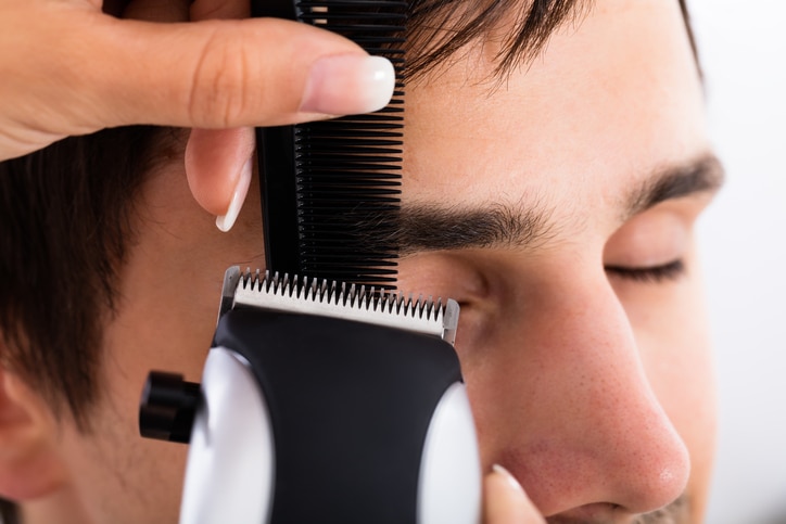 Close-up Of A Hairdresser Cutting Man's Hair At Salon