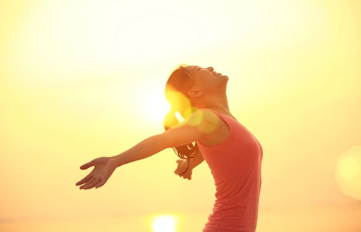 cheering woman open arms under  sunrise on beach